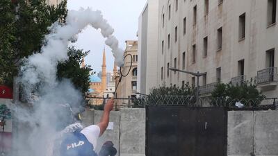 An anti-government protester uses a tennis racket to return a tear gas canister towards riot police near Parliament Square in Beirut on September 1. AP