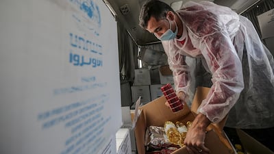 A Palestinian worker at the United Nation Relief and Works Agency (UNRWA) distributes food aid rations for refugee families, in Gaza City. EPA